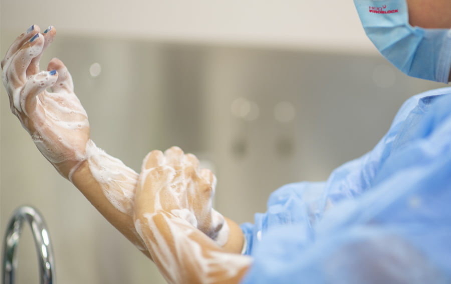Surgeon washing hands in PPE antiviral treated gown and face mask