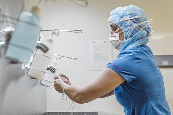 Surgeon washing hands in PPE treated gown and face mask
