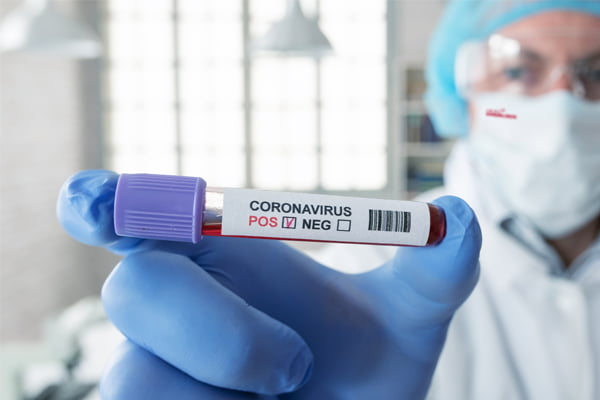 Scientist in antiviral PPE holding vial of Corona virus