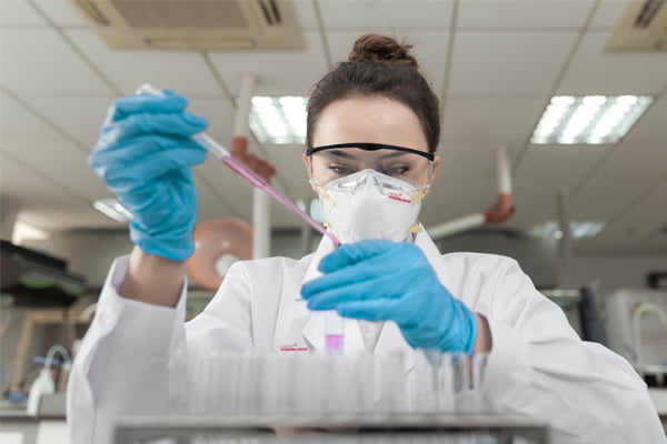 Scientist in laboratory wearing PPE gloves, gown and face mask